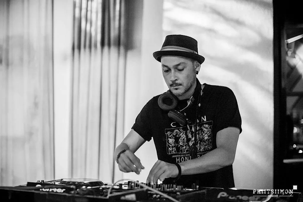 DJ CMAN in a hat working the decks, shot in black and white